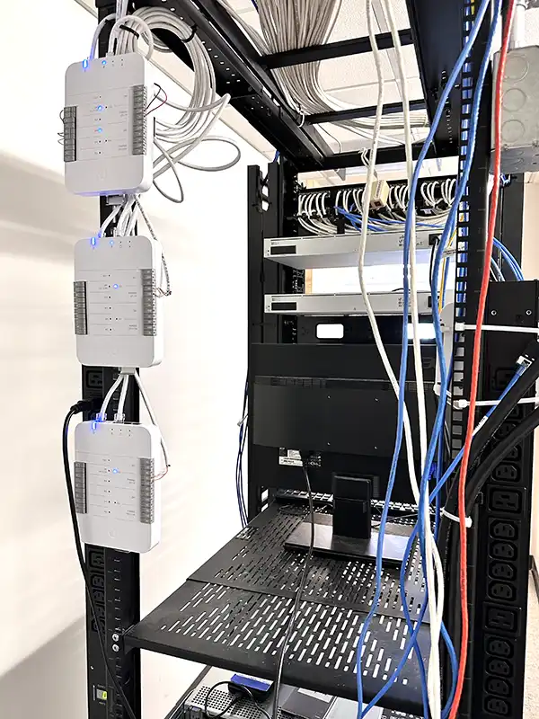 UniFi Access control system installation — multiple access hubs mounted in a commercial network rack alongside patch panels and structured cabling, installed by Alpine IT in Colorado Springs, CO